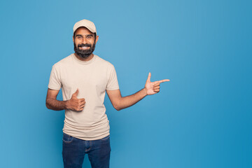 Fototapeta premium A man wearing a white shirt and a white cap is using his finger to point at something out of frame. He appears focused and engaged in the act of directing attention towards copy space
