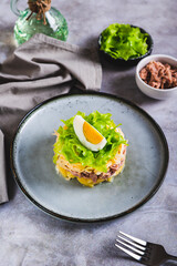 Hearty canned tuna salad with vegetables and herbs on a plate vertical view