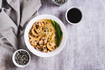 Funchose rice noodles with mushrooms and green onions in a bowl on the table top view