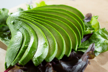 A closeup view of sliced avocado on top of a salad.