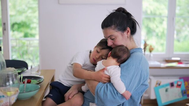 Mother holding both a baby and a young child, smiling warmly. joyful and nurturing side of parenthood in a cozy indoor setting