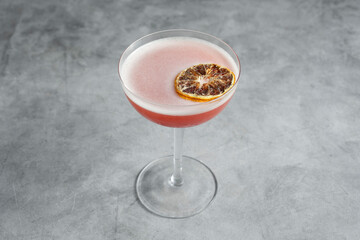 A view of a pink colored cocktail in a coupe glass.