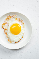 A top down view of a fried egg on a plate.