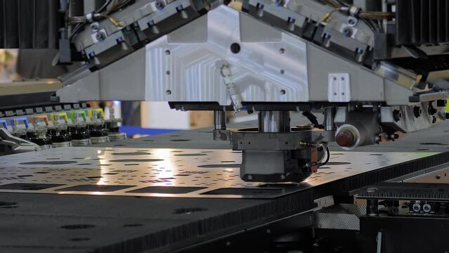 Automatic CNC punch press machine is operating on sheet metal at factory, plant: process of creating holes, shapes. Concept of metalworking, industrial, technology, machining and manufacturing
