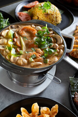 A view of a bowl of tom kha goong, among other Asian entrees.