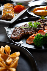 A view of a plate of crying tiger, among other Asian entrees.