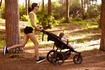 Beautiful young woman runs with a stroller.