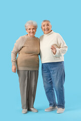 Senior female friends hugging on blue background