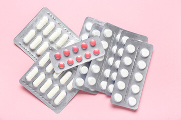 Blister packs with different pills on pink background