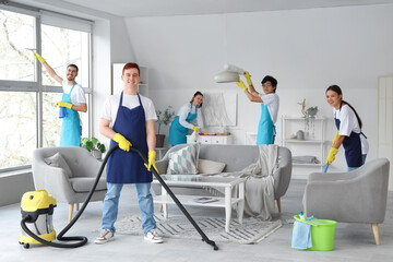 Team of young janitors cleaning in room