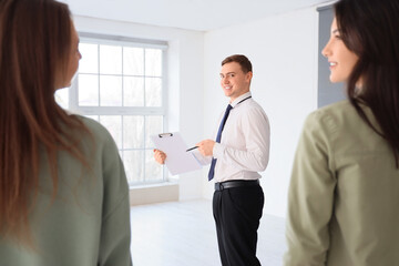 Real estate agent with clipboard showing young lesbian couple new house
