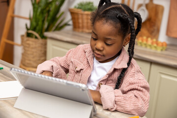 Little girl browsing internet on her tablet exploring educational websites for her school project