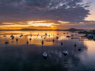 Aerial sunrise waterscape with boats, clouds and reflections