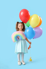 Cute little girl with balloons and toy rainbow on blue background