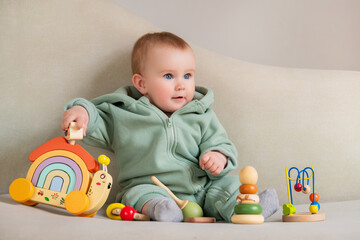 A baby is sitting on a couch with a toy car and a toy house.