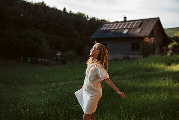 Little girl in front of house with solar panels on roof, jumping, dancing and having fun. Concept...