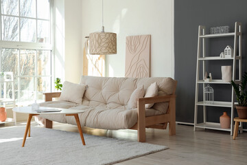 Light interior of modern living room with comfy sofa, coffee table and shelving unit