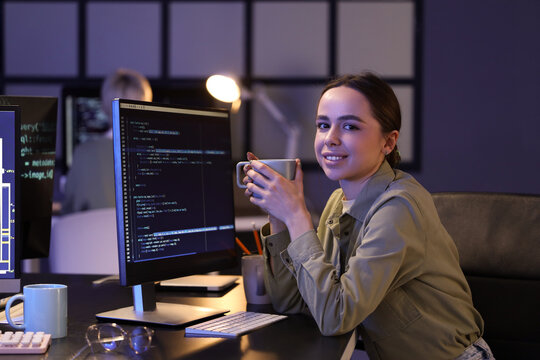 Female programmer with coffee cup sitting in office at night