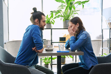Obraz premium Serious young couple arguing, quarreling sitting together in cafeteria