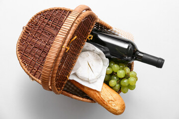 Wicker basket with tasty food and drink for picnic on white background. Top view