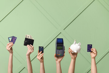 Female hands with credit cards, wallet, piggy bank and payment terminal on green background