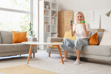 Mature woman with massage balls sitting on sofa at home