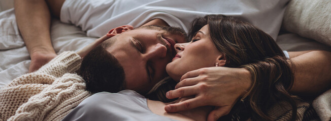 Banner relationships. Beautiful happy loving young couple relaxing in bed, looking at each other....