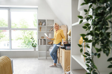 Mature woman using laptop and printer at home