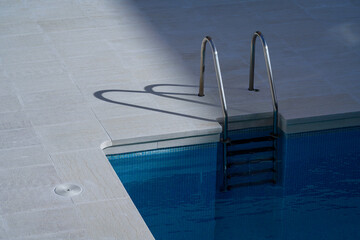 Obraz premium the shadow of a pool ladder is cast on the ground