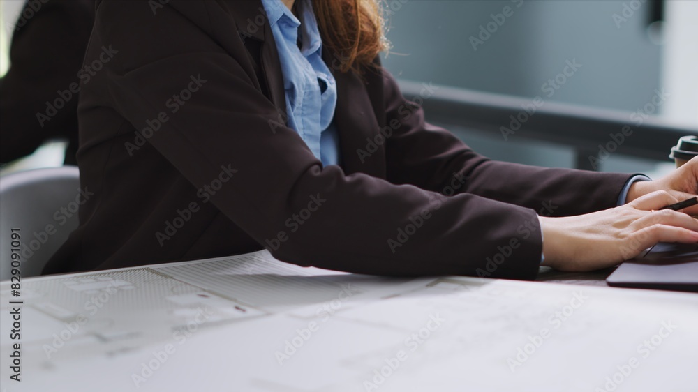 Poster interior designer studying architectural blueprints in office to translate accurate measurements of 
