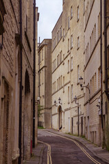 A narrow street flanked by tall stone buildings in the historic City of Bath in Somerset England