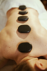 Woman having hot stone massage and laying on massage table