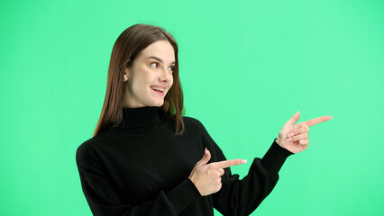 A woman, close-up, on a green background, points to the side