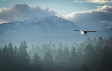 A small biplane makes its way in for a landing among the mountains in Comox, BC. © Thomas E. Lee