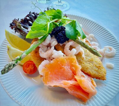 Traditional Danish open sandwich with fried plaice fillet, cold water shrimps, smoked salmon and lumpfish caviar (Stjerneskud)