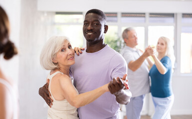 African-American man dances steamy salsa with elderly female companion for fitness classes and enjoys movement and activity. Hobbies, active pastime