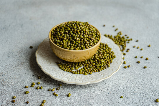Close-up of a bowl of mung beans (Vigna radiata) overflowing onto a plate and table