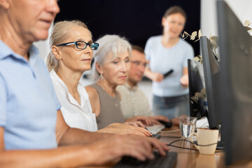 Side view of elderly people while studying in computer lab in nursing home