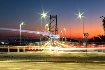 noite e as luzes do tráfego intenso de carros e ônibus na ponte Hercílio Luz de Florianópolis,...