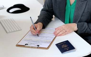 Top view close up of a woman filling out visa application documents with an American passport
