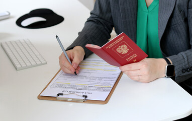 Top view close up of a woman filling out visa application documents with a Russian passport