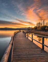 Fototapeta premium A serene scene unfolds with a wooden pier extending over a tranquil lake, bathed in the warm glow of sunset during the summer 