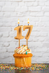 Cupcake with number 17 birthday candle - White block wall background