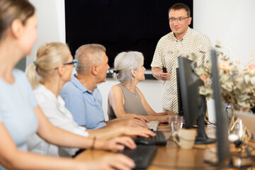 Inspiring instructor leading computer session for older adults. Concept of digital education for...