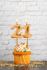 Cupcake with number 21 birthday candle - White block wall background