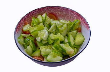 Vegetable salad of fresh cucumbers, tomatoes and herbs in a plate, isolate on a white background.
