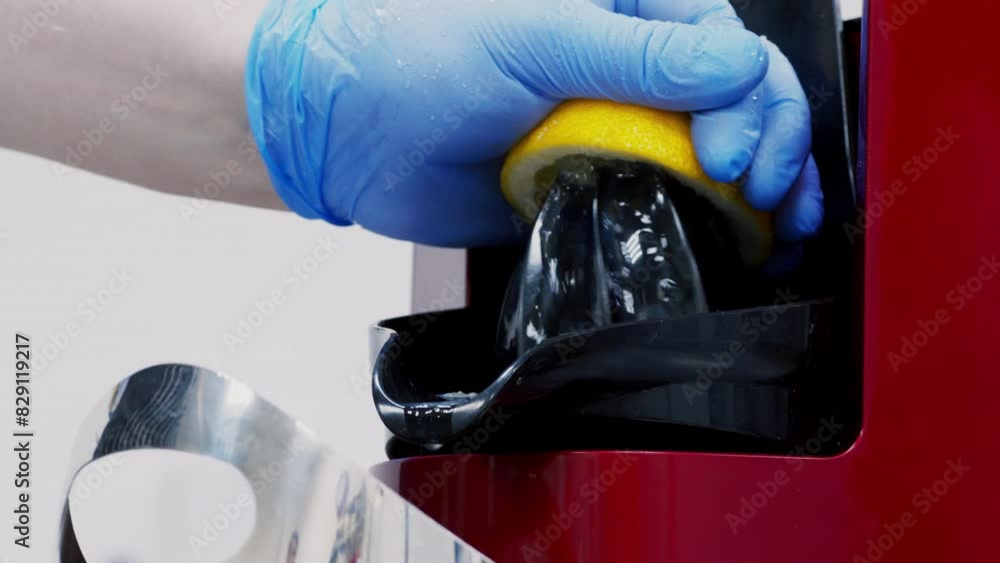 Poster making lemonade. chef squeezing fresh lemon with electric juicer at kitchen, close up