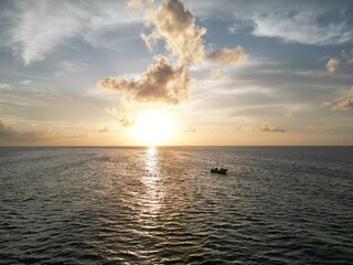 Beautiful sunset scene with the shilouette of a boat with two people. View from above with aereal view from a drone. Picture from san andres islands, Colombia.