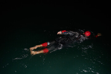 A determined professional triathlete undergoes rigorous night time training in cold waters,...