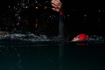 A determined professional triathlete undergoes rigorous night time training in cold waters,...